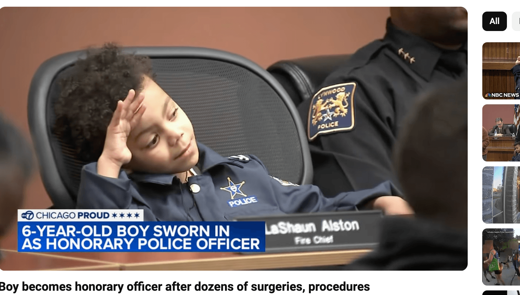 Little boy sitting in a chair wearing a police uniform.
