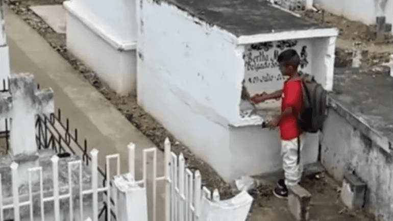 boy wearing a black backpack at a graveyard