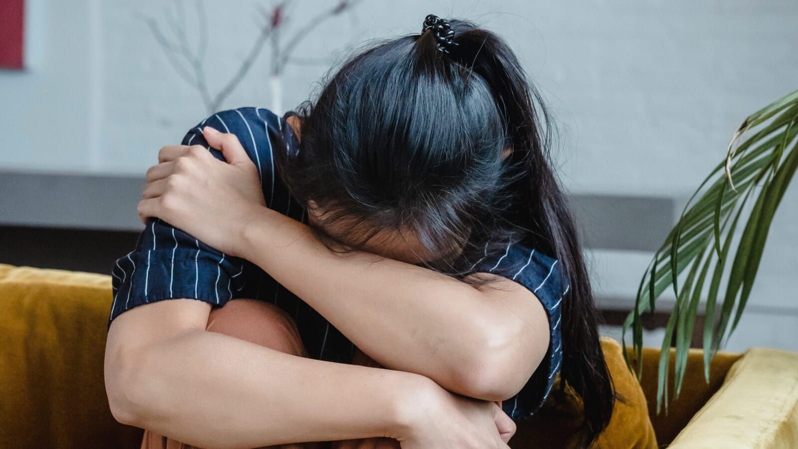 woman in a ponytail crying on the couch