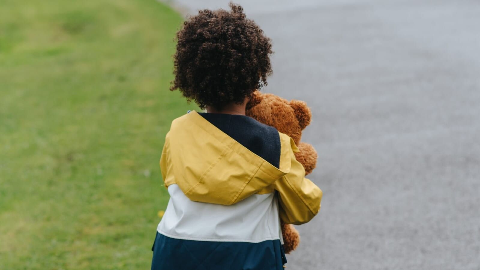 little boy holding a stuffed toy and walking on the street alone