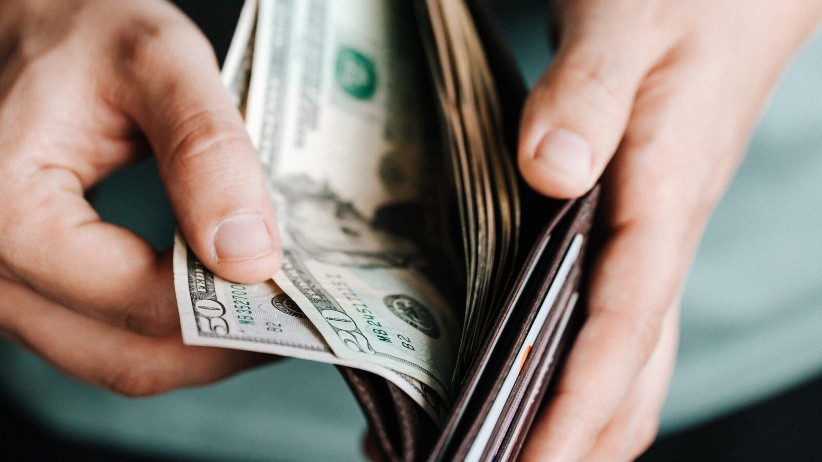 person opening a wallet with money in it