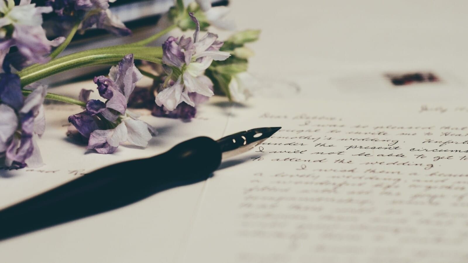 a pen sitting on a letter next to flowers