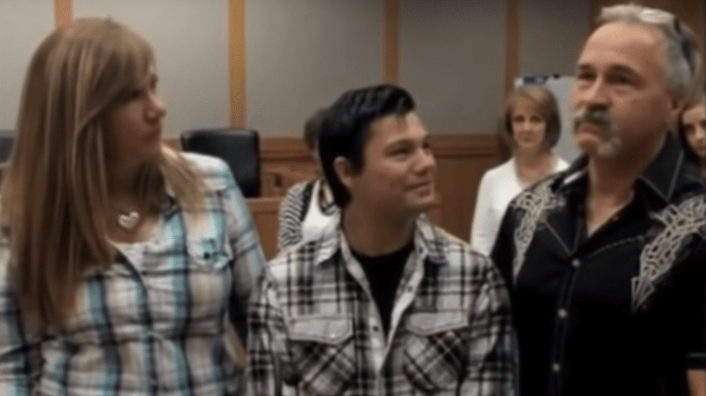 a teen boy standing in between a man and a woman