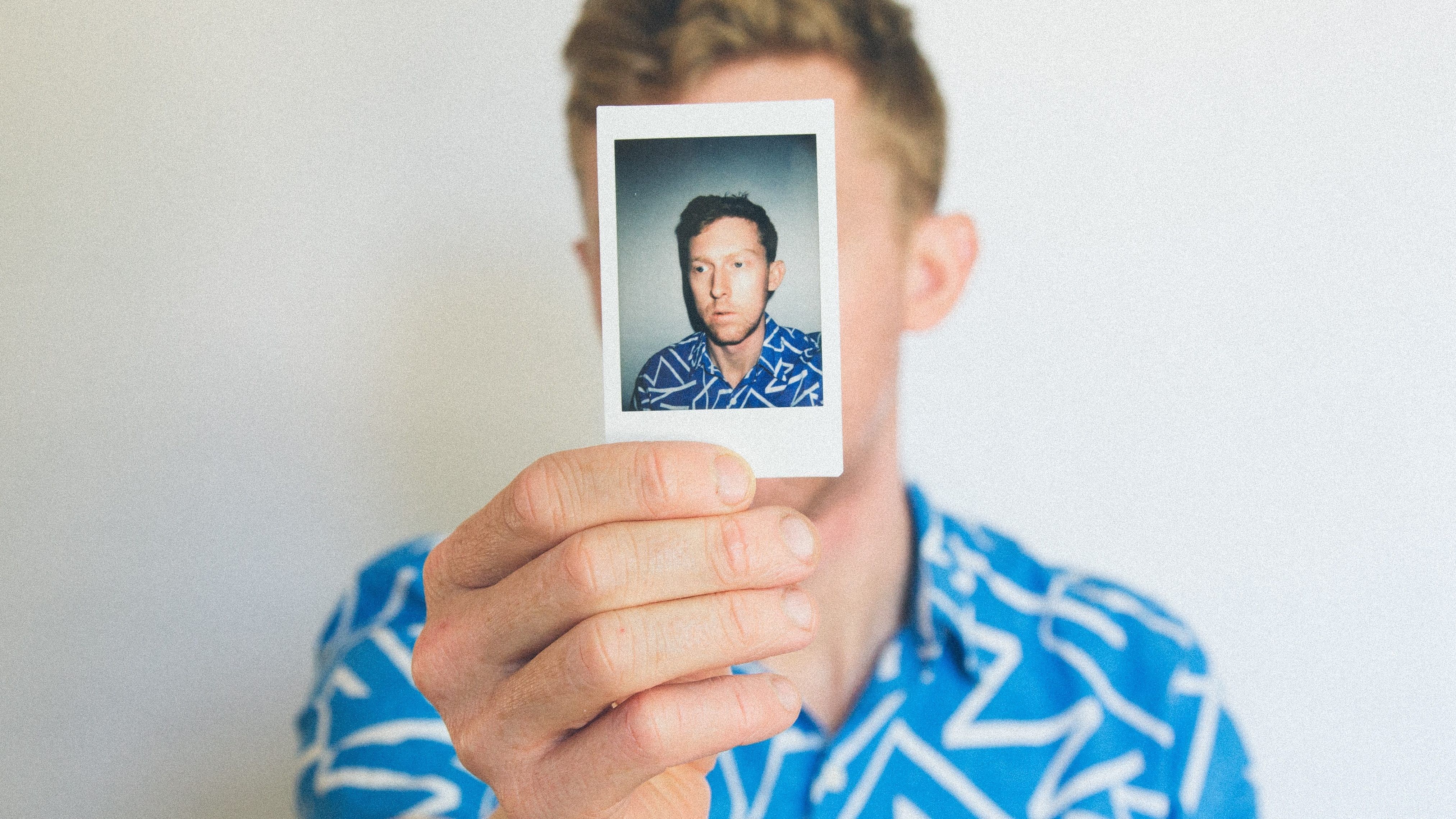 man holding a polaroid picture of himself