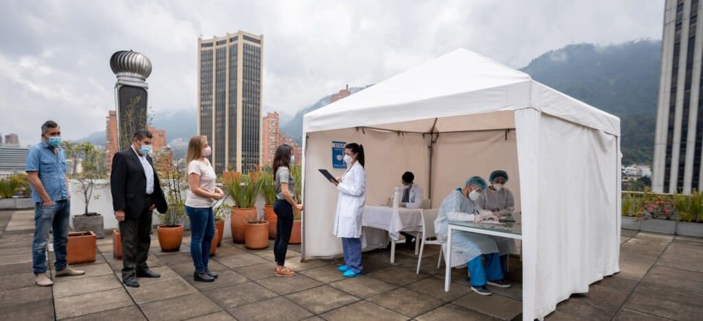 Group of Latin American people in line waiting to get their COVID-19 vaccine at a vaccination stand - immunization program concepts