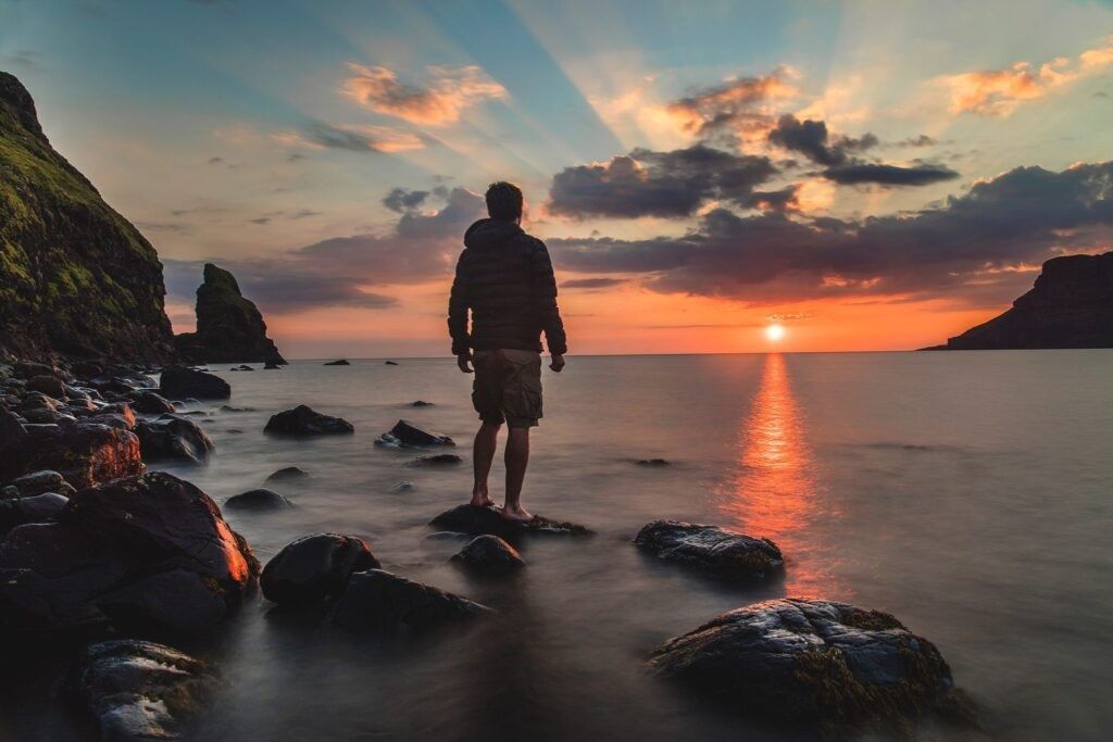 man-standing-rock-looking-sunset