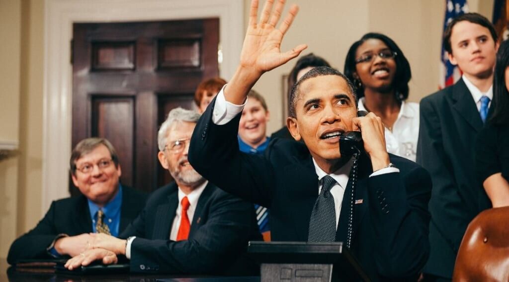 U.S. President Barack Obama in 2010 waves as he talks on the phone from the Roosevelt Room of the White House by History in HD on Unsplash