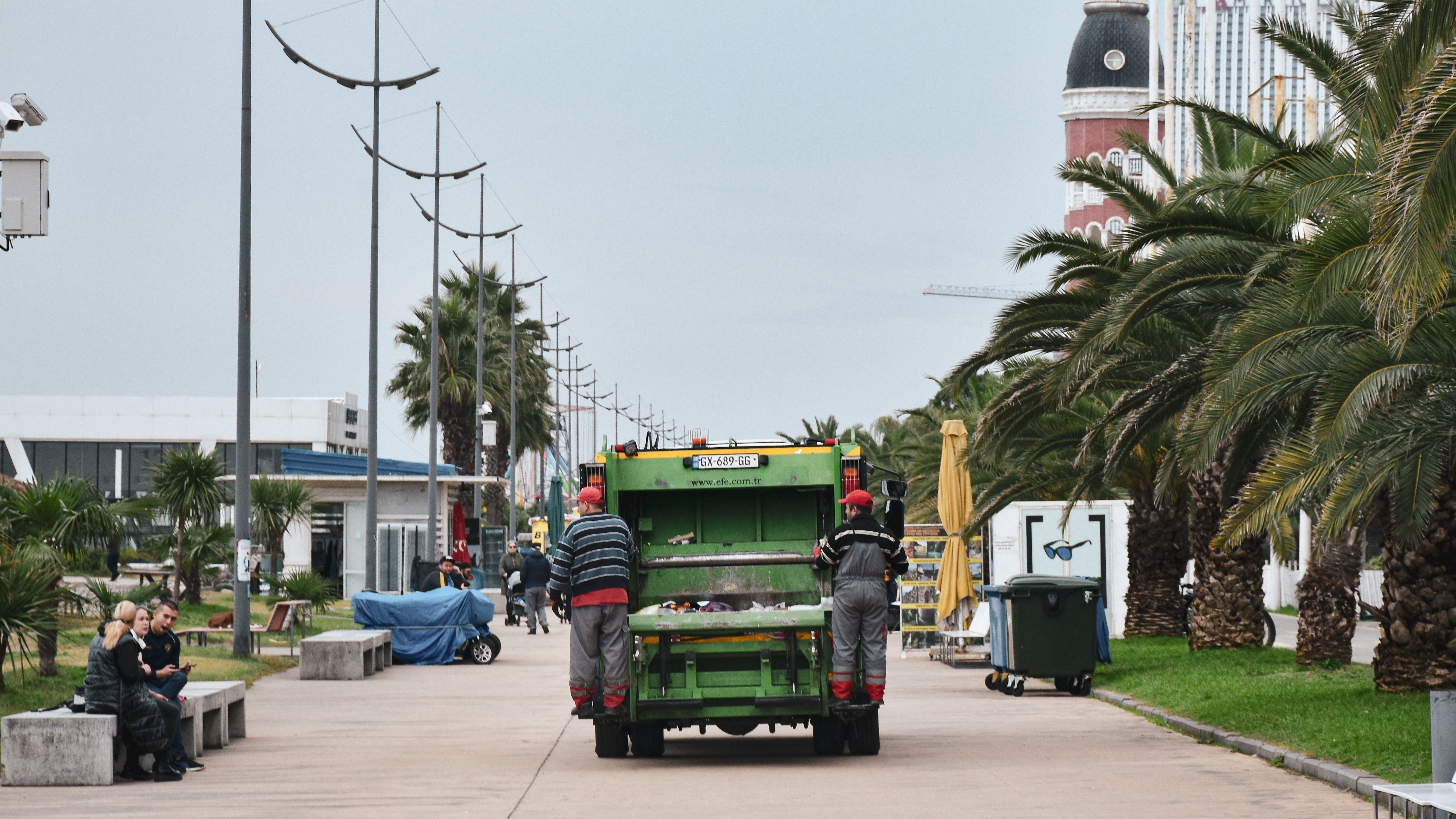 a garbage truck with two sanitation workers