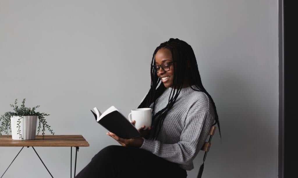 woman reads book smiling sitting at table