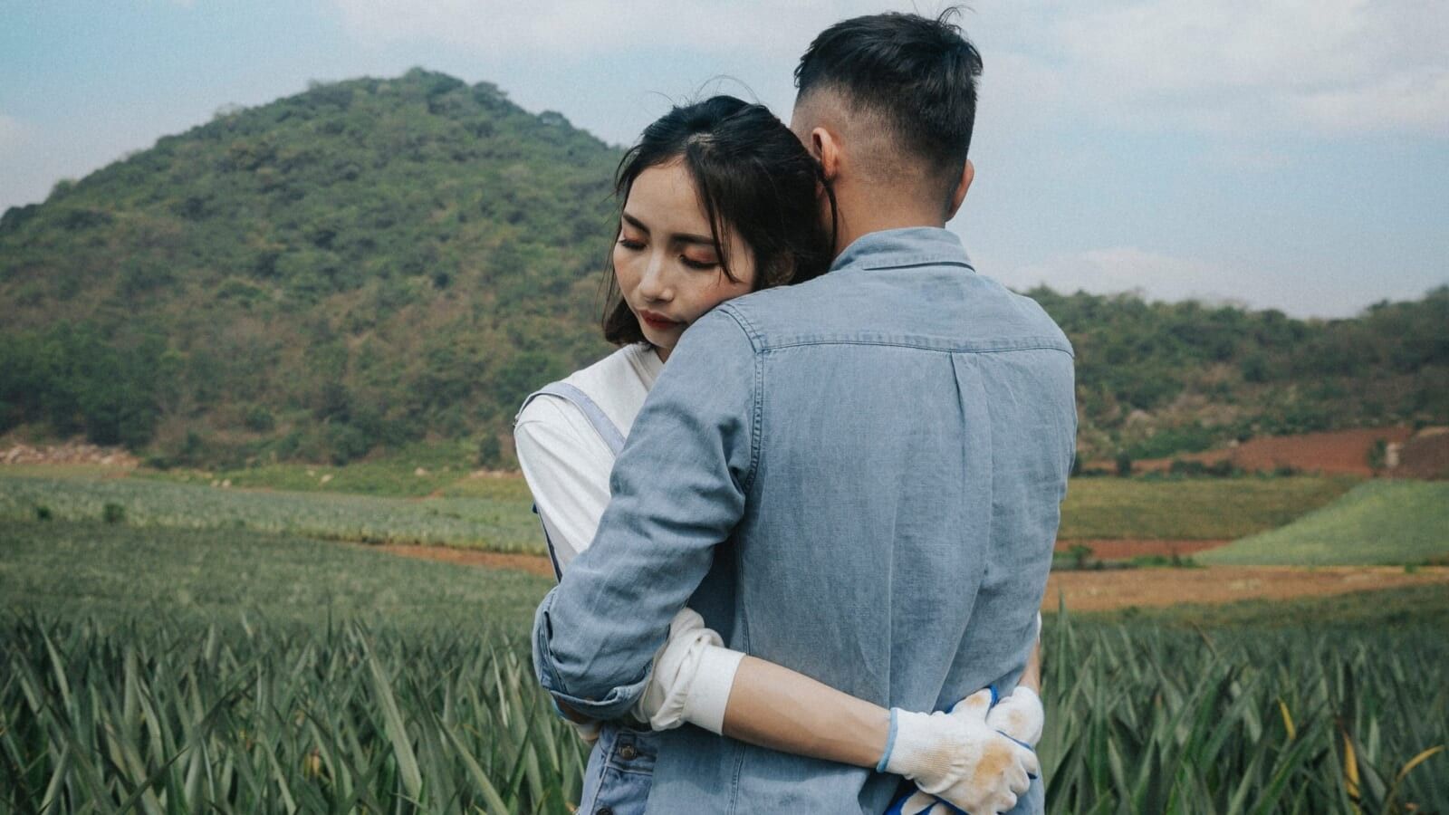 man hugging a woman in a green field