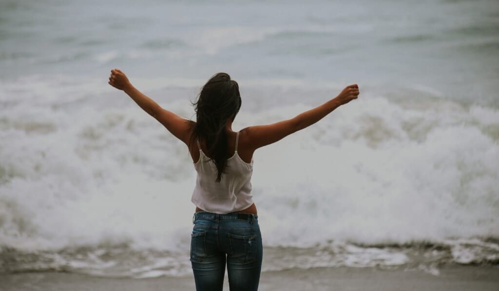 woman lets the ocean serenade her spirit