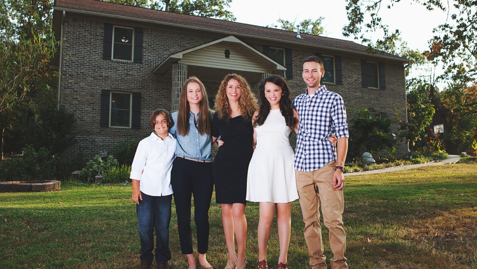 five people standing in front of a house