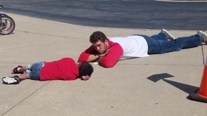 man laying on the ground next to a student