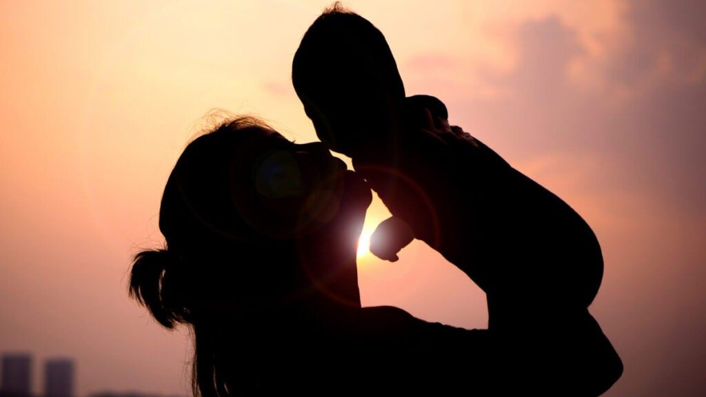 A mother kissing a child in silhouette 1024x576