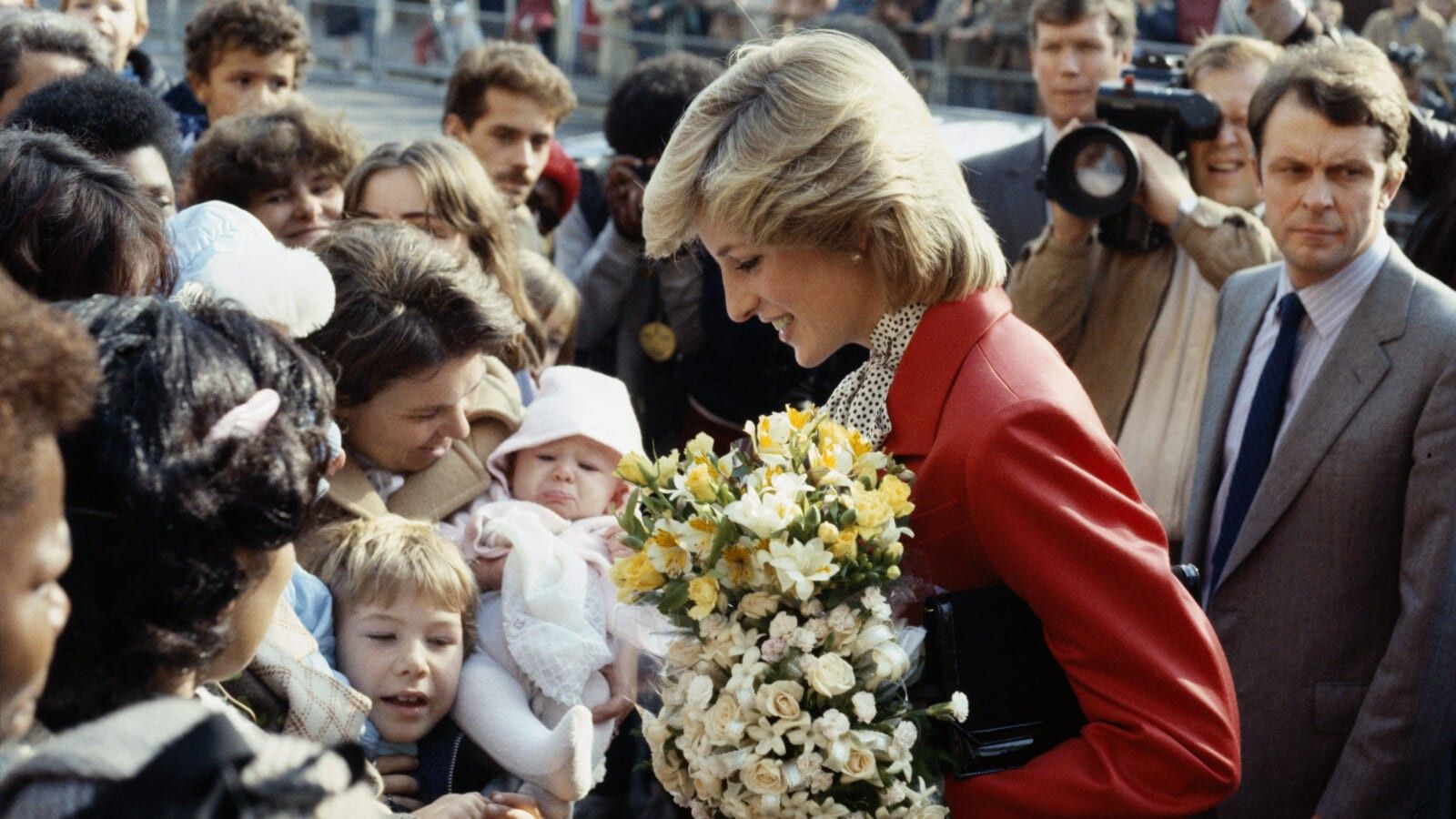 woman holding a bouquet and smiling at a lot of people - kids and adults