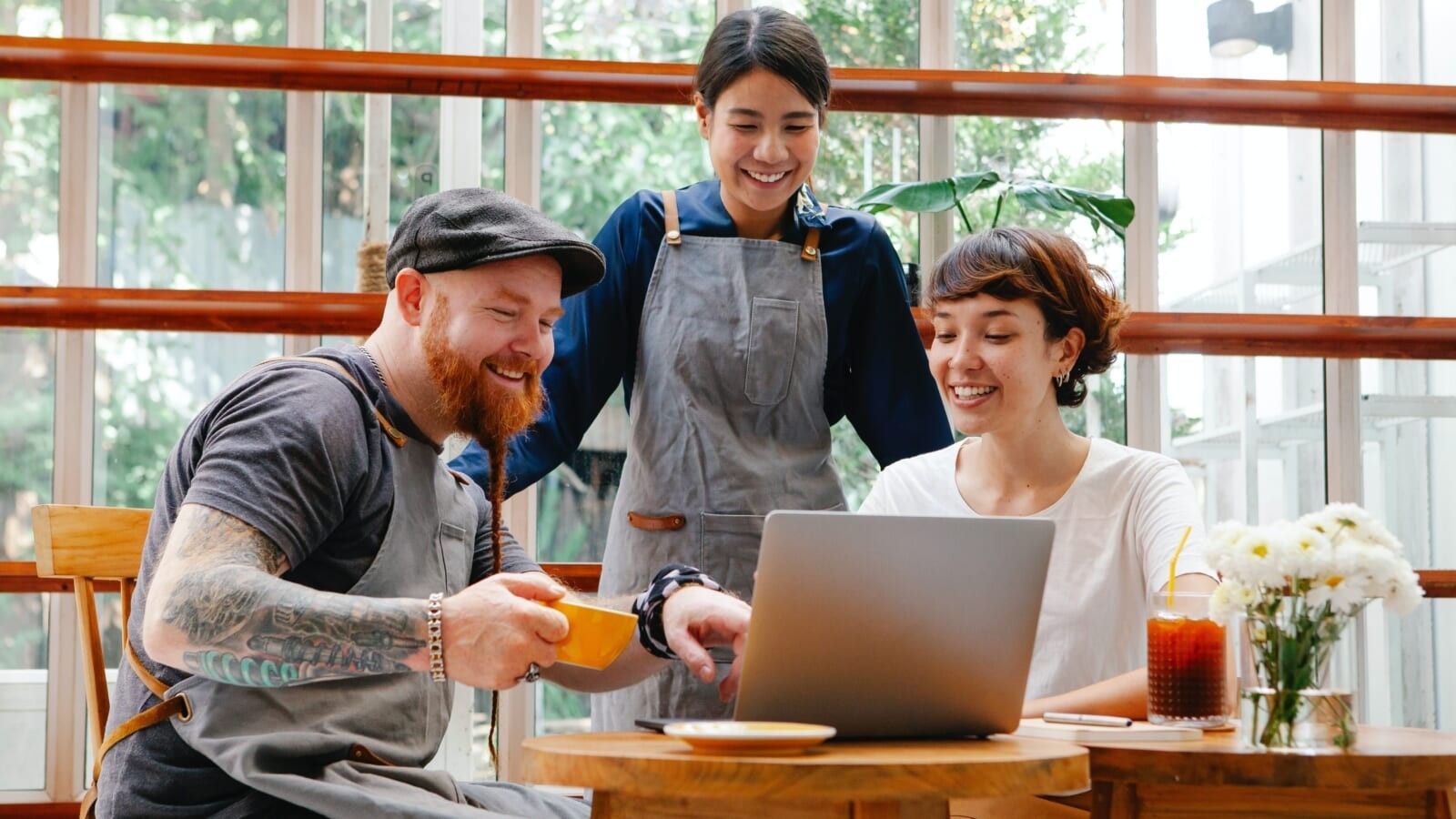three people looking at a laptop in a cafe