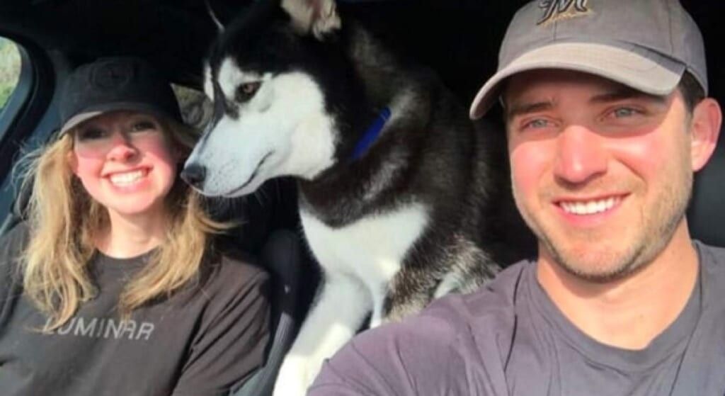 Elizabeth Holmes in a car with her husband their husky.