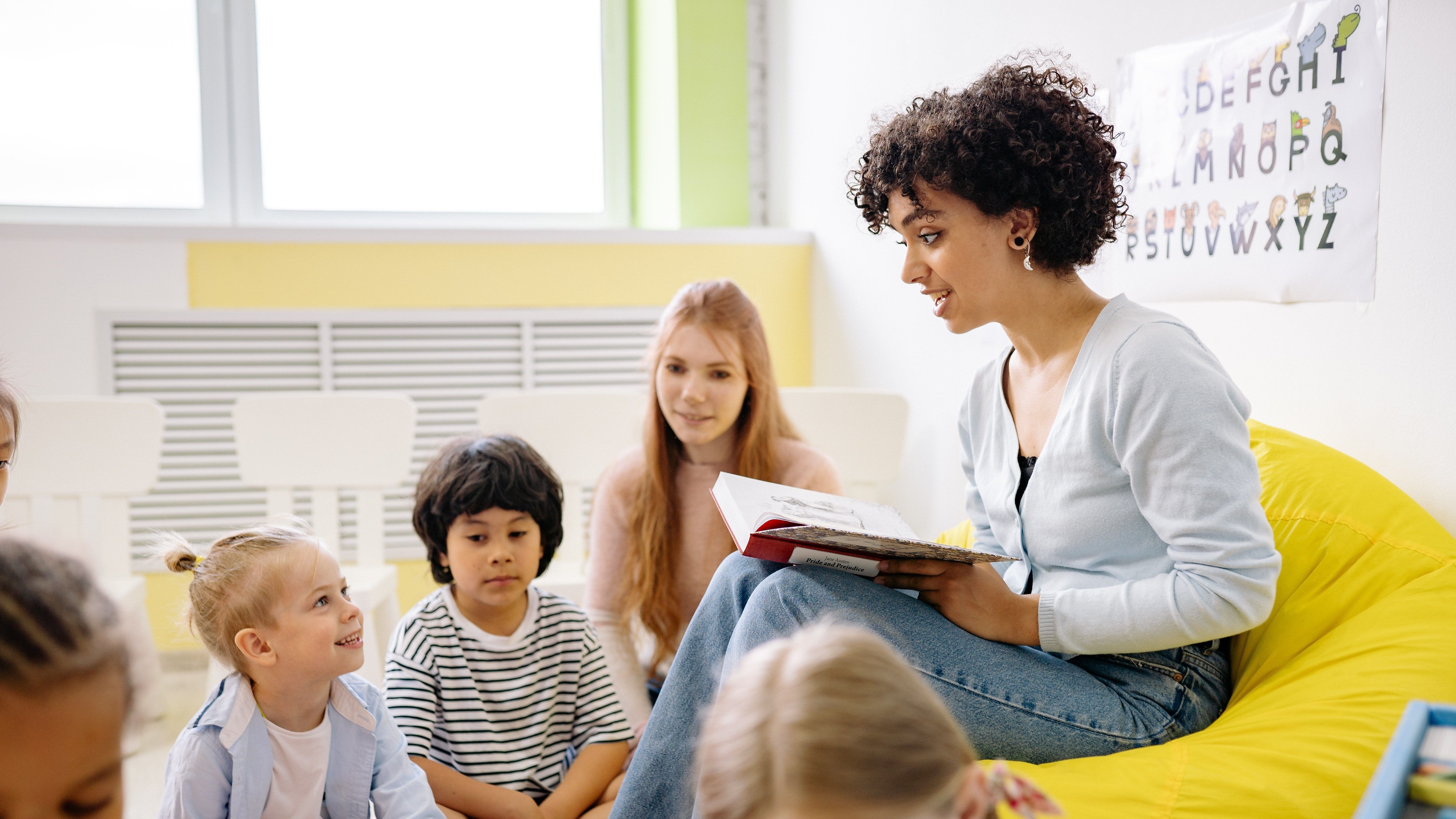 woman reading a book to a group of children