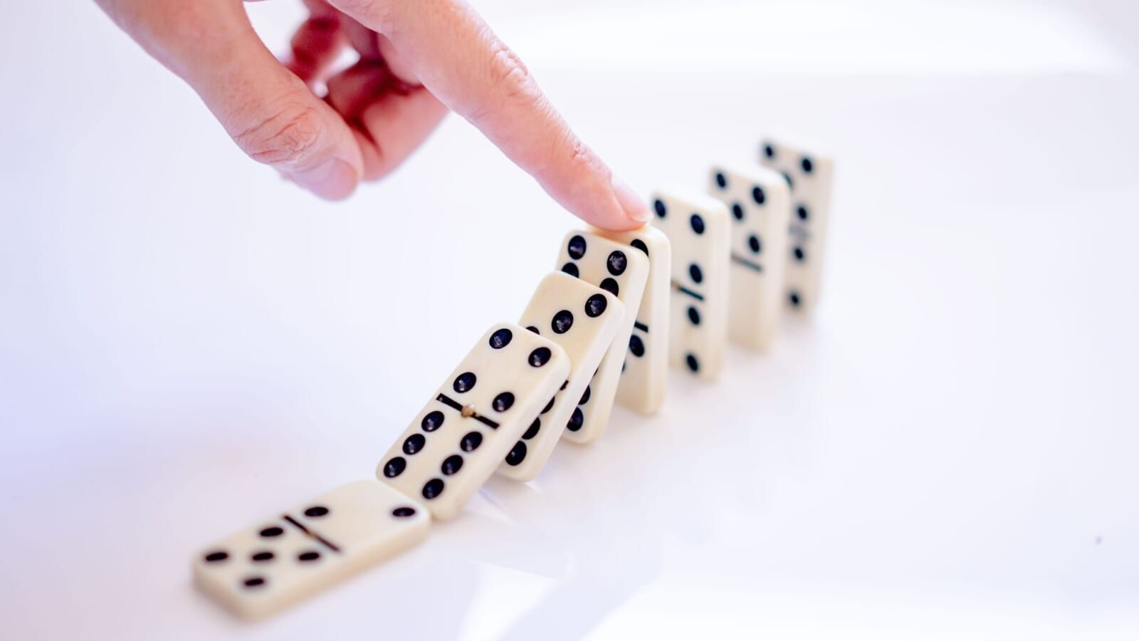 person touching falling dominos