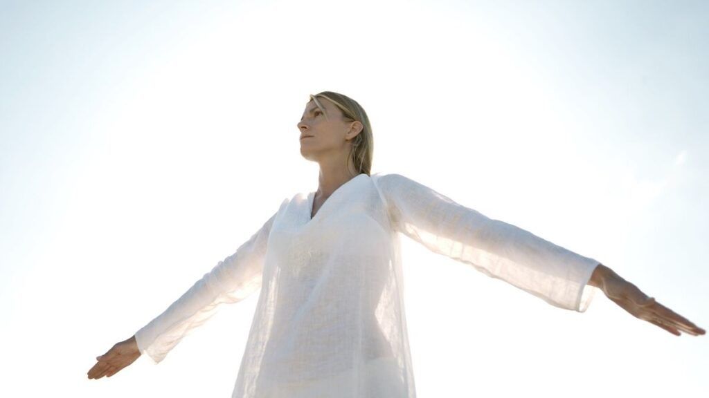 Woman in white robe outside, clear skies