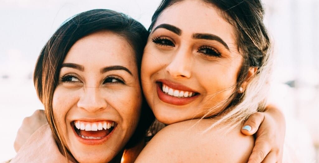 two young women smile and pose together