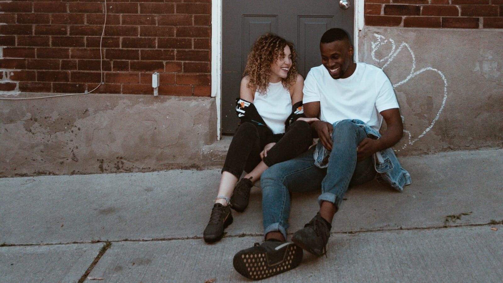 man and woman sitting outside a door