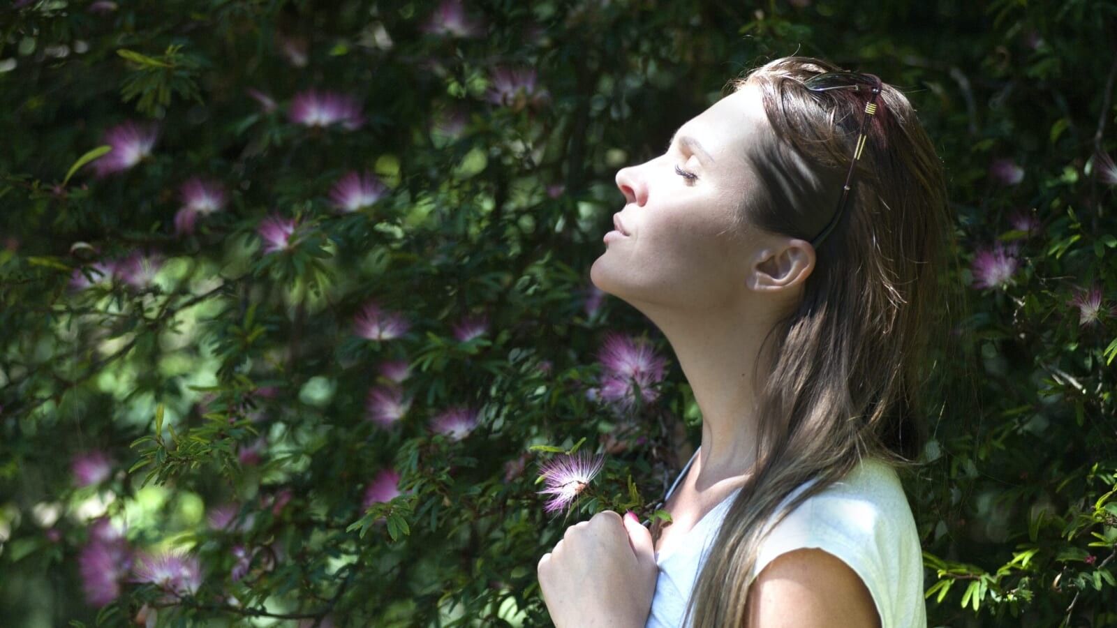 woman standing outside with her face to the sun