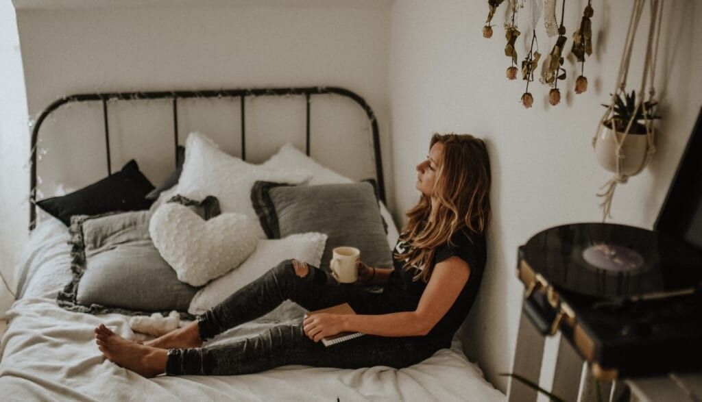 young woman sits on bed