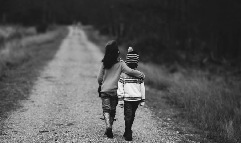 sad children walking down dirt road