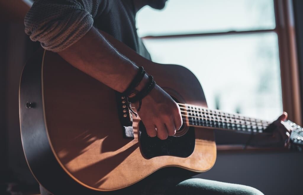 young person plays guitar with immense passion