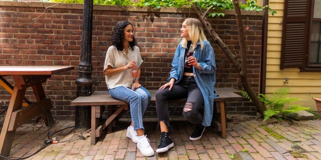 Two women on a bench talking and having a soda by Jarritos Mexican Soda on Unsplash
