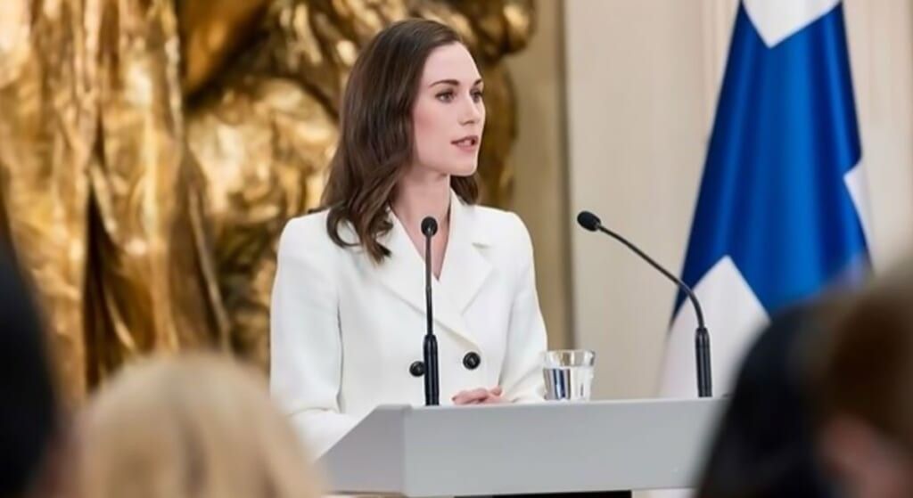 Finland Prime Minister Sanna Marin holding a conference wearing a white suit.