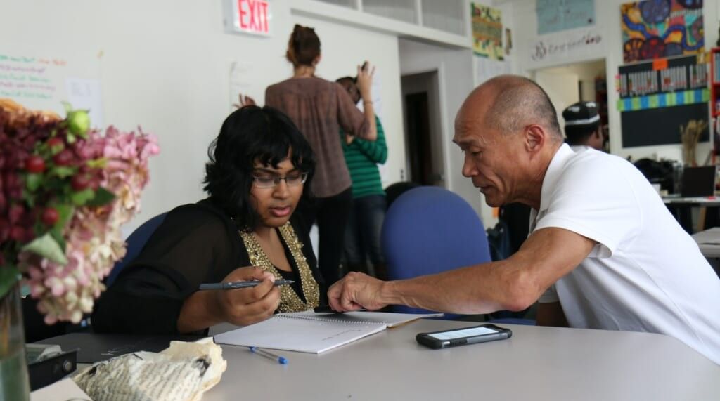 one adult teaches another at table