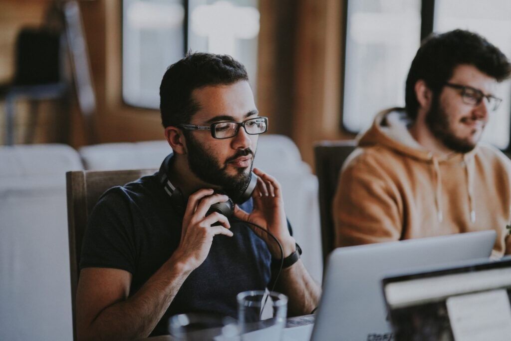 man-taking-off-headphones-while-working-laptop
