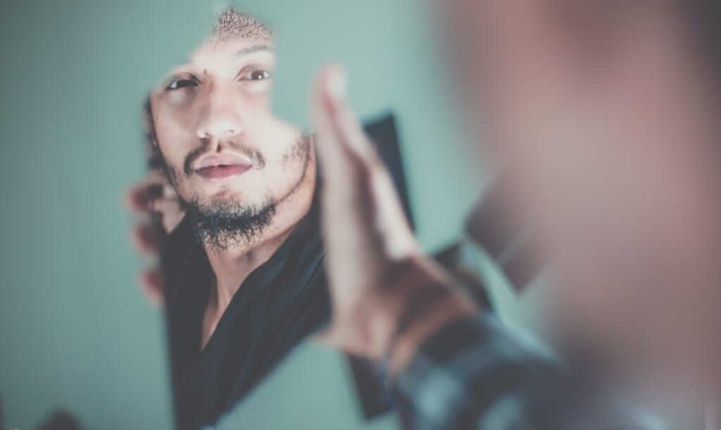 man look into mirror and reflects on his life