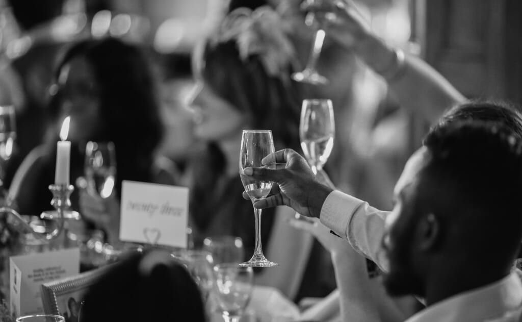 wedding guests holding up champagne glasses to toast