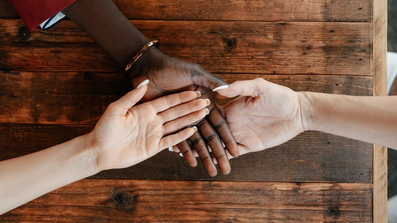three hands from diverse backgrounds one on top of the other