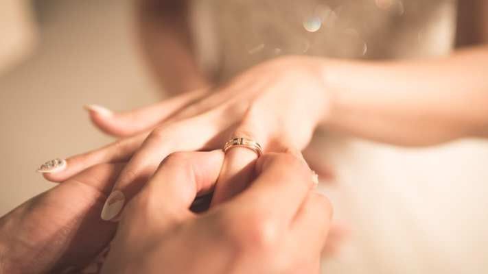 Groom placing ring on bride