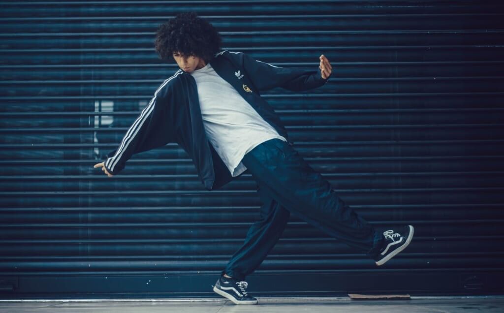 young man dances in front of blue backdrop