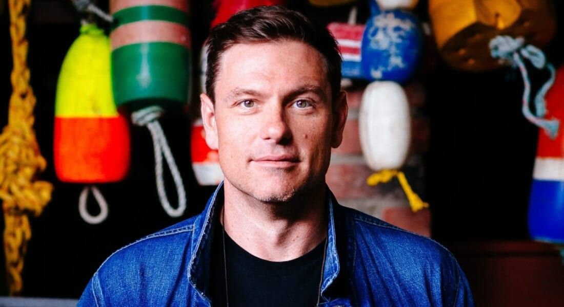 Chuck Hughes smiling at the camera in his kitchen.