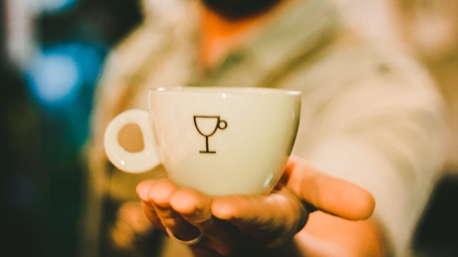 man holding a coffee cup in the palm of his hand