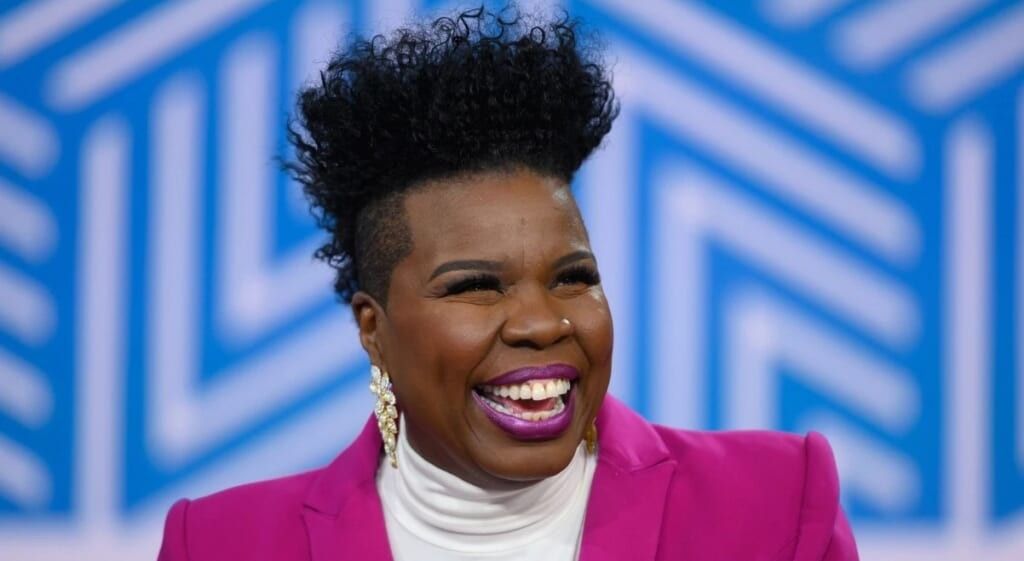 Leslie Jones in pink suit laughing during an interview