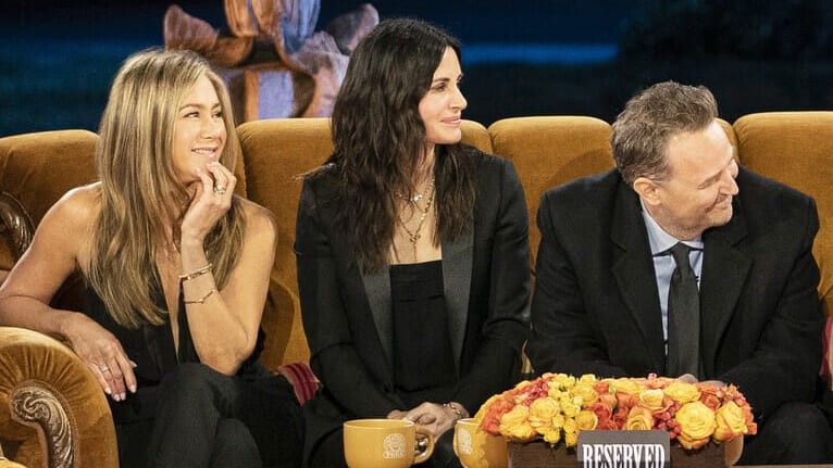 two women and one man sitting on a couch