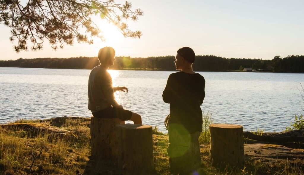 young people having a chat by the lake on sunny day