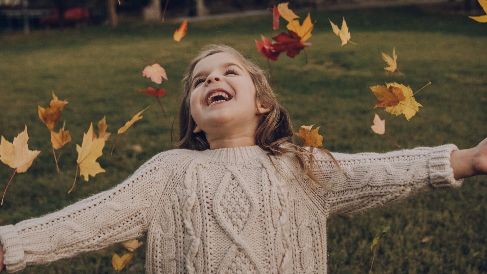 little girl playing with falling leaves