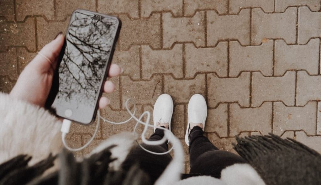 person holds phone listening to podcast outside