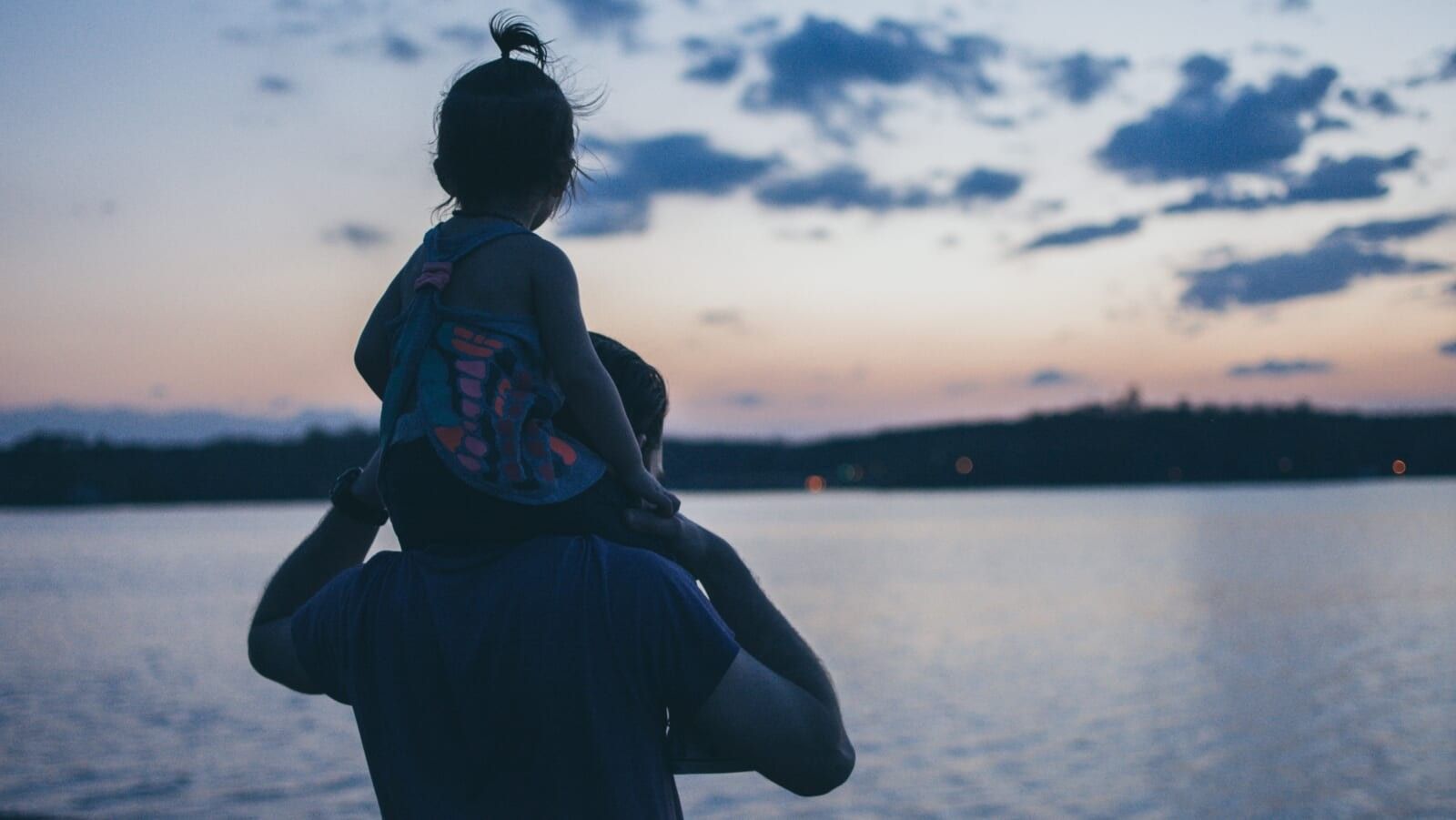 man carrying a little girl on his shoulders