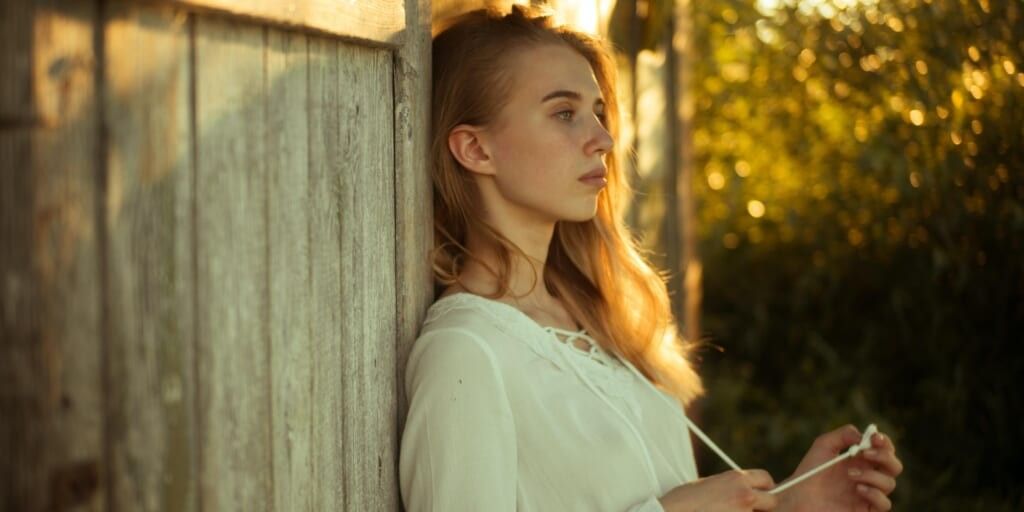 Woman wearing white top leaning on wooden wall by Masha Raymers on Pexels