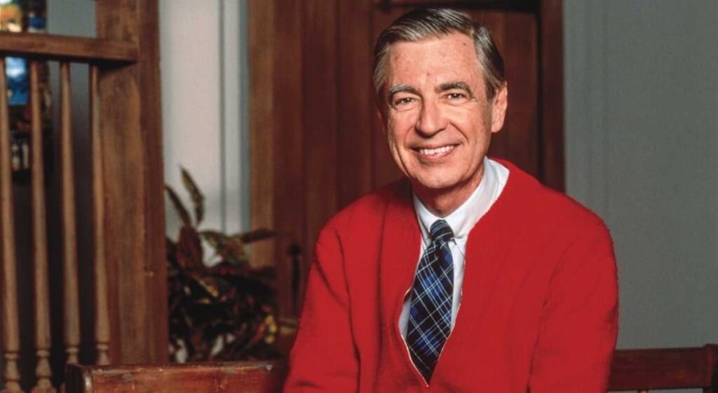 Mr. Rogers smiling at the camera in a red sweater