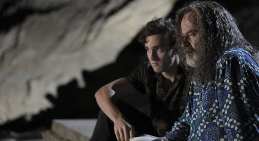 Kelsey Grammer with beard sitting on a rock in The Space Between